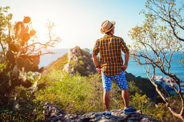 Mutlu adam uçurumun kenarında durur ve seyahatin tadını çıkarır. Tatiller, tatiller..