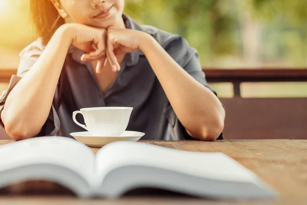 teacup on wood table in front of woman smile and relaxing between read a book.