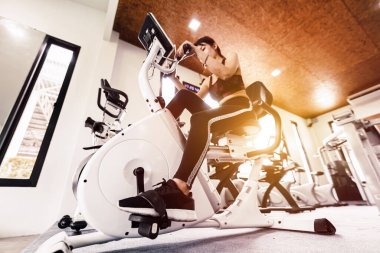 Spor salonunda egzersiz bisikletine binen formda bir kadın. Sağlıklı ve komik yaşam tarzı kavramı.
