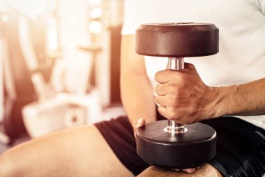 Spor salonunda dambılı tutan bir adam.