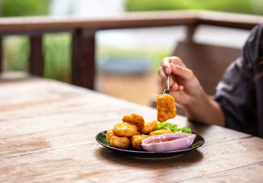 Tavuk Nuggets bir çatal ve Dip sos üzerine kazıklı. Bir kadın Nuggets yemek.
