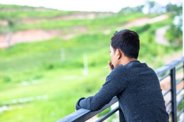 Otelin balkonunda sigara içen bir adam..