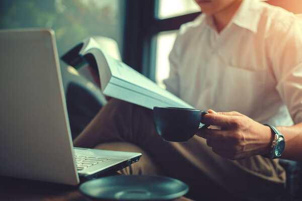 Businessman hold cup of coffee and read a book. Enjoying  coffee in the morning.