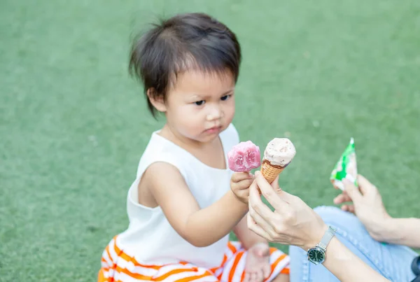 asian child and mom eating ice-cream together in the park