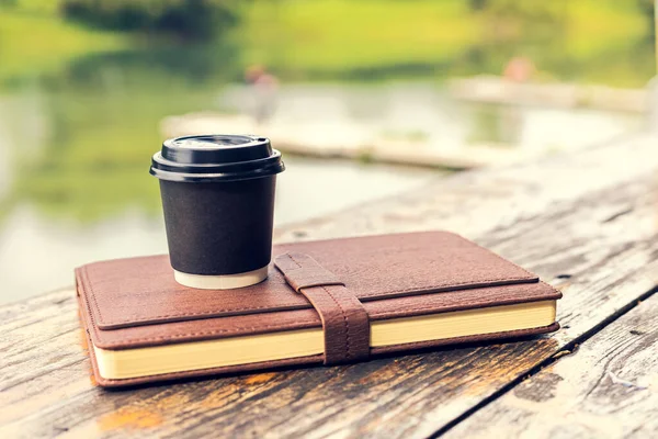 Little cup of coffee on the book near the river.