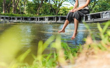 Nehrin üzerindeki köprüde oturan bir kadın.