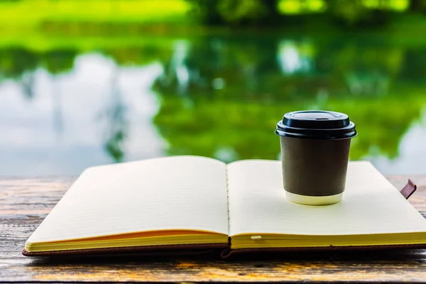Little cup of coffee on the book  in the morning near the river.