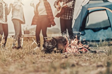 Kamp ateşinde bir adam arkadaşlarıyla gitar çalar. Aktif açık hava eğlencesi. Etkin dinlenme.