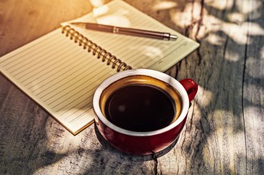 Kahve fincanı kâğıt parçasının yanındaki masada..