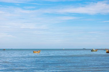 Mavi sularda ve mavi gökyüzünde balıkçı teknesi.
