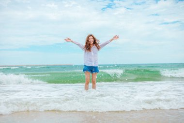 Genç kadın tropik sahilde eğleniyor özgürce su sıçratmaca oynuyor..
