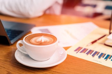 Kağıt grafik ve dizüstü bilgisayarın yanındaki masada..