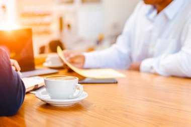 Kitap, kağıt grafik, dizüstü bilgisayar ve masada kahve. Toplantı arasında kahve molası.