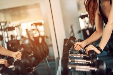 Kadınlar, spor salonunda dambıl kaldırarak egzersiz yaparlar. Spor salonunda spor yapan kadınlar..