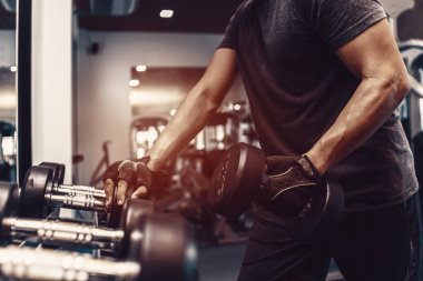 Spor salonunda dambılı kaldıran genç bir adam. Fitness, spor salonu, egzersiz ve stil konseptini kaldırma.