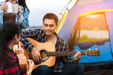 Bir grup arkadaş göl ve dağ kenarında seyahat edip kamp yapıyorlar. Gitar çalan adam eli..