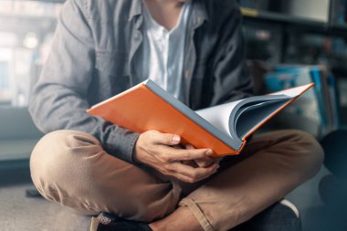 Bir adam kütüphanede kitap açıp okuyor..