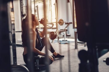 Kadın spor salonunda antremandan sonra mola verip su içiyor..