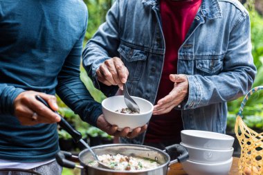 Bir adam yemek tatmak için kaşık kullanır..