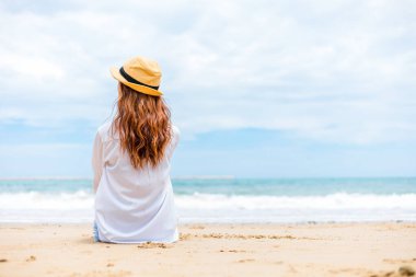 Güzel bir kadın portresi ve kumsalda oturan bir şapka.