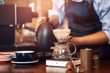 Çaydanlıktan damlayan kahve makinesine kaynar su döken barista..