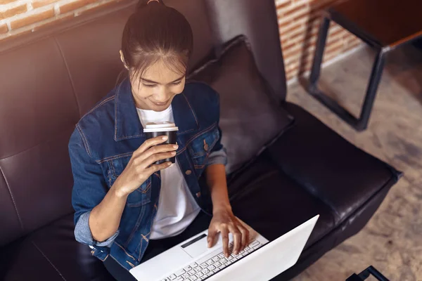 Mujer Joven Sentada Sofá Cafetería Tomando Café Mientras Trabaja Computadora — Foto de Stock