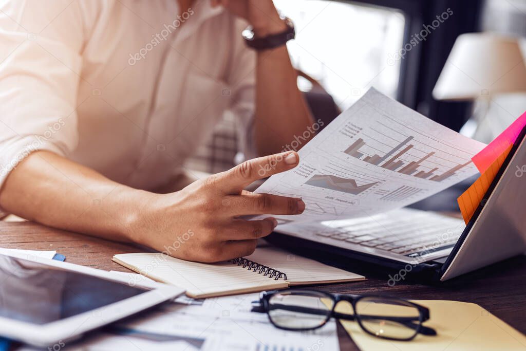 Businessman hold pen and working calculate data. document graph chart and report marketing. Business office concept.