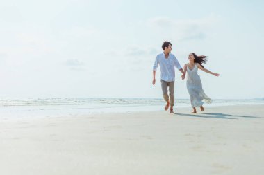 Kumsalda koşan ve yürüyen romantik bir çift. Aşık bir adam ve kadın.