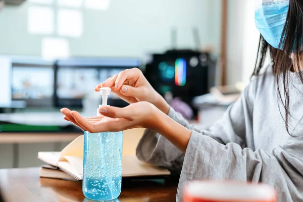 Working from home. Cleaning hands with sanitizer gel. Business woman working from home wearing protective mask.