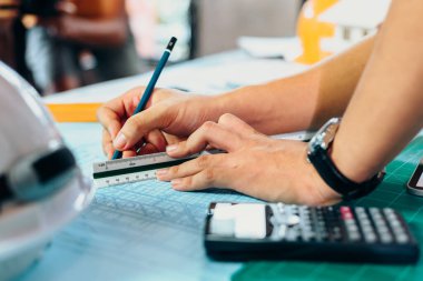 Bir binayı işaret eden bir kalem tutan mühendisler, inşaatçılar için ayrıntılı bir kılavuz olarak çıkış planı çiziyorlar.