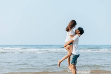 Romantik çift kumsalda sevişiyor ve sarılıyor.