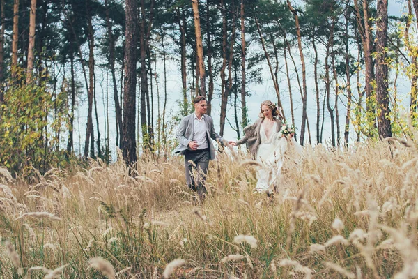 a laughter lovely couple are running in the forest holding the h