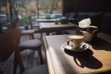 Ahşap masa ve güneş ışığı ile rahat kafede kahve