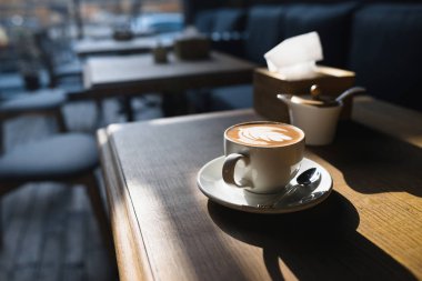 Bir fincan kahve ahşap masa ve güneş ışığı 