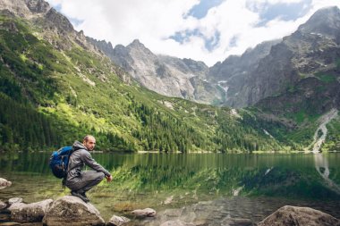 Kayanın üzerinde bir dağ Gölü kıyısında oturan adam bir manzara sahiptir