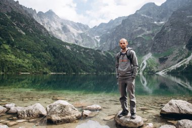 Bir dağ Gölü kıyısında bir kayanın üzerinde kalan adam