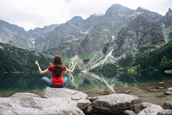 Jovem mulher fitness meditando na margem do lago da montanha — Fotografia de Stock