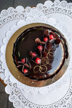 Kahverengi kek çikolata sır ile kaplı ve kırmızı meyveler ve altın tozu ile dekore edilmiş