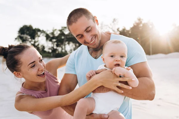 Счастливая эмоциональная семья: мама, папа держит маленького мальчика на закате — стоковое фото