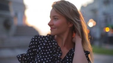 Güzel bayan güneşin doğuşuna karşı duruyor ve saçları düzeltiyor.