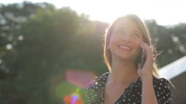 Uzun saçlı neşeli model modern akıllı telefondan konuşuyor.