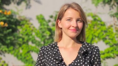 Şık kız poz verir ve parlak yaz güneşine hayran kalır.