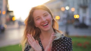 Uzun saçlı komik bayan alkışlar ve şehir manzarasına karşı dans eder