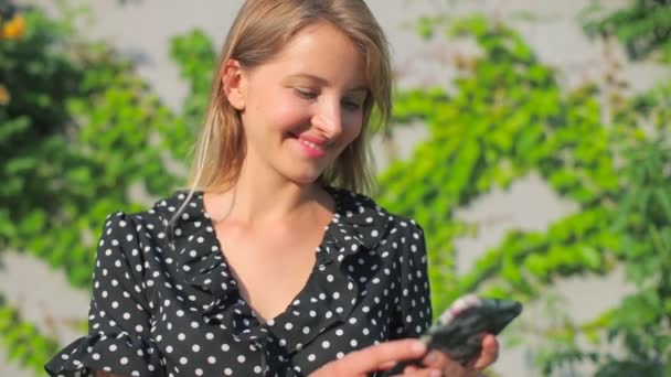 Csinos hölgy típusok okostelefon és nevet nyáron — Stock videók