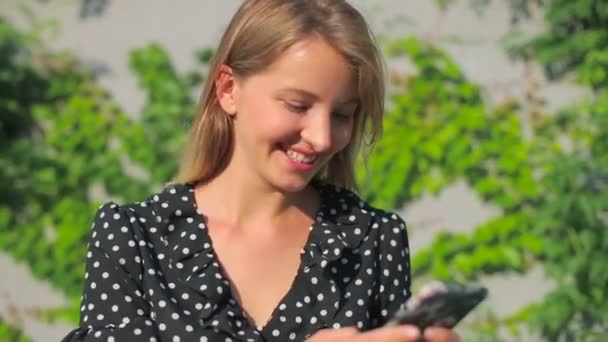 Tipos de rubia con estilo en el teléfono inteligente moderno con sonrisa — Vídeos de Stock