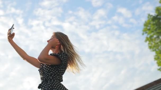 Mujer joven en vestido de verano fija el cabello y hace selfie — Vídeo de stock
