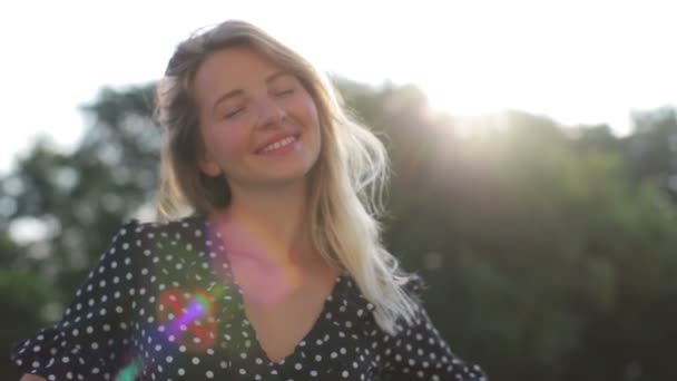 Fille à la mode pose avec le sourire contre les arbres verts flous — Video