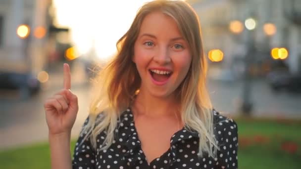 Blonda apare și ridică degetul arătător împotriva răsăritului soarelui — Videoclip de stoc