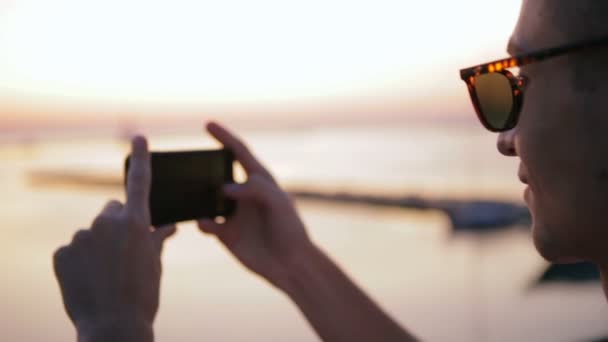 Kille tar bilder av imponerande sol mot suddig havsutsikt — Stockvideo