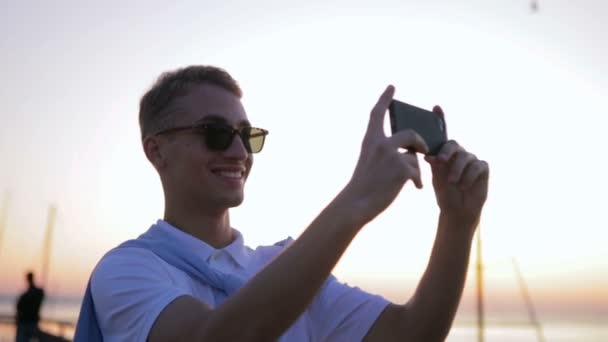 Chlap kráčí podél promenády a dělá video z městských scenérií — Stock video